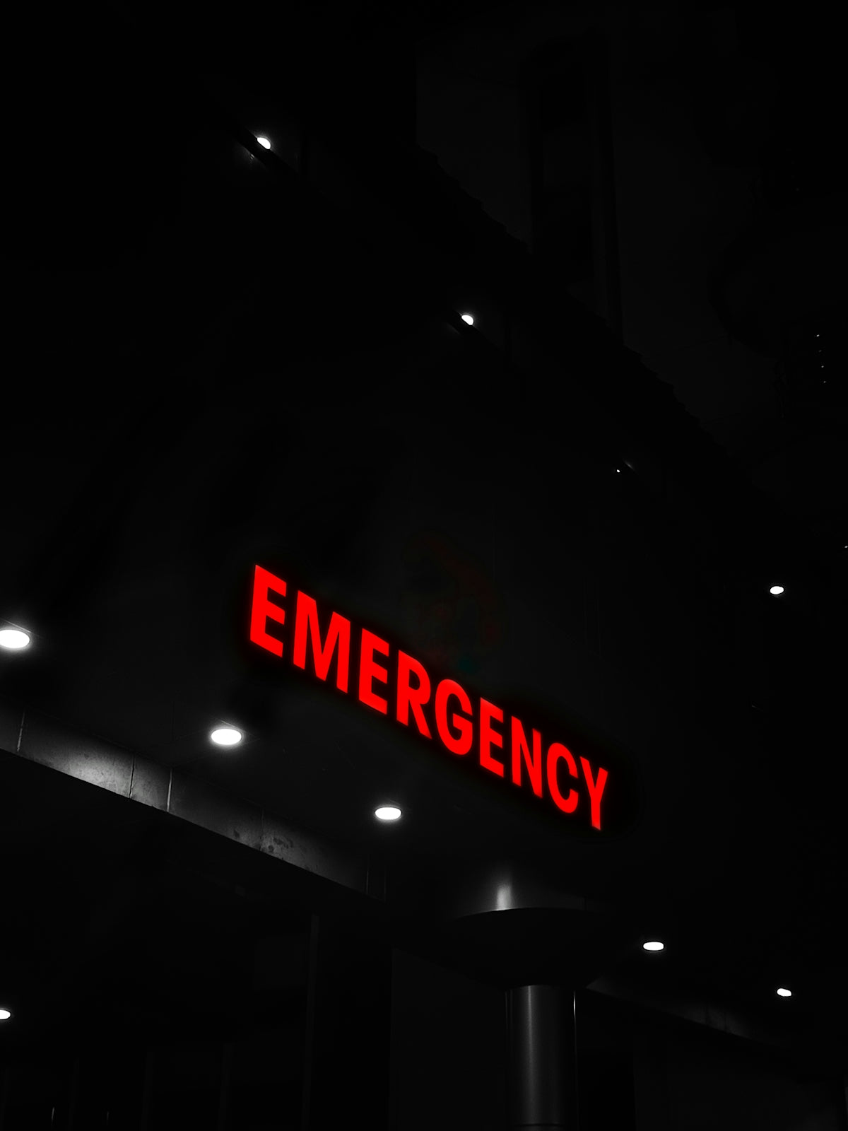 Red emergency sign illuminates a dark building entrance.