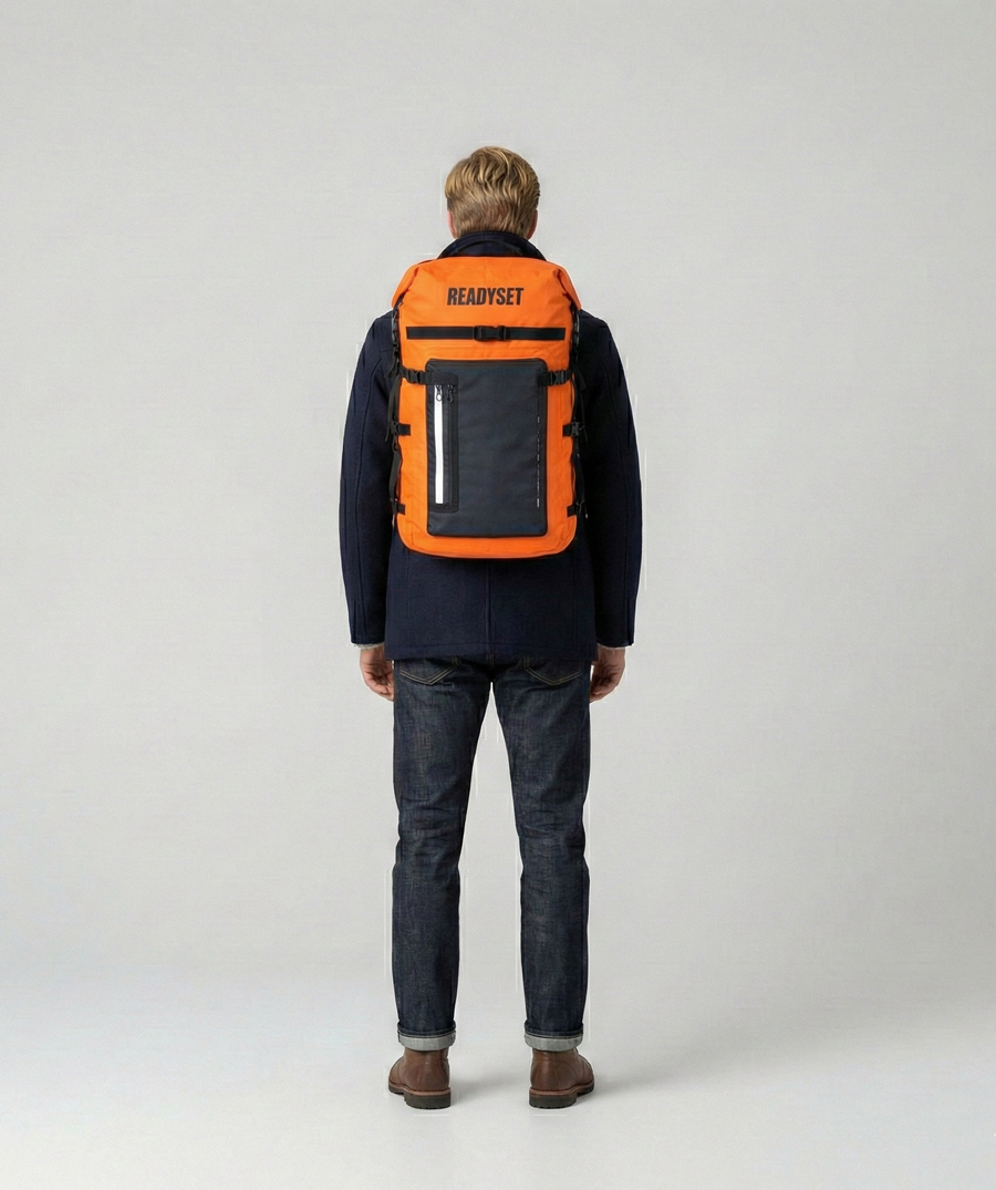 Person with orange ReadySet Solo Set emergency backpack on a plain background