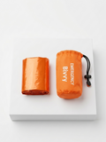 Orange emergency bivy sack with packaging on a white background